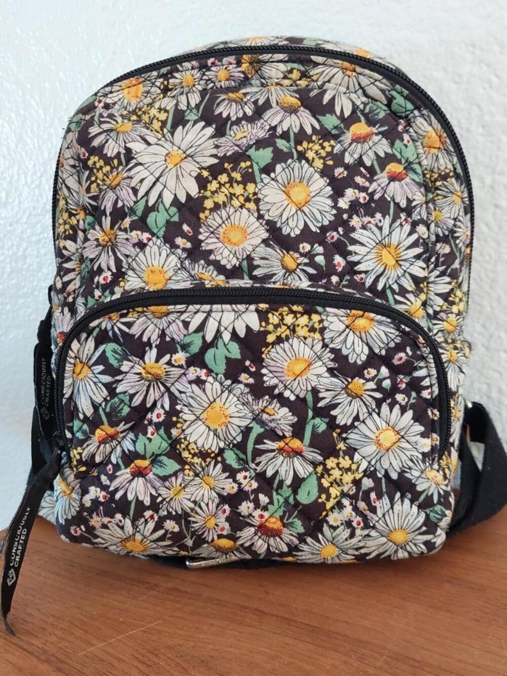 Vera Bradley Daisy Floral Backpack with white daisies and yellow centers on a da